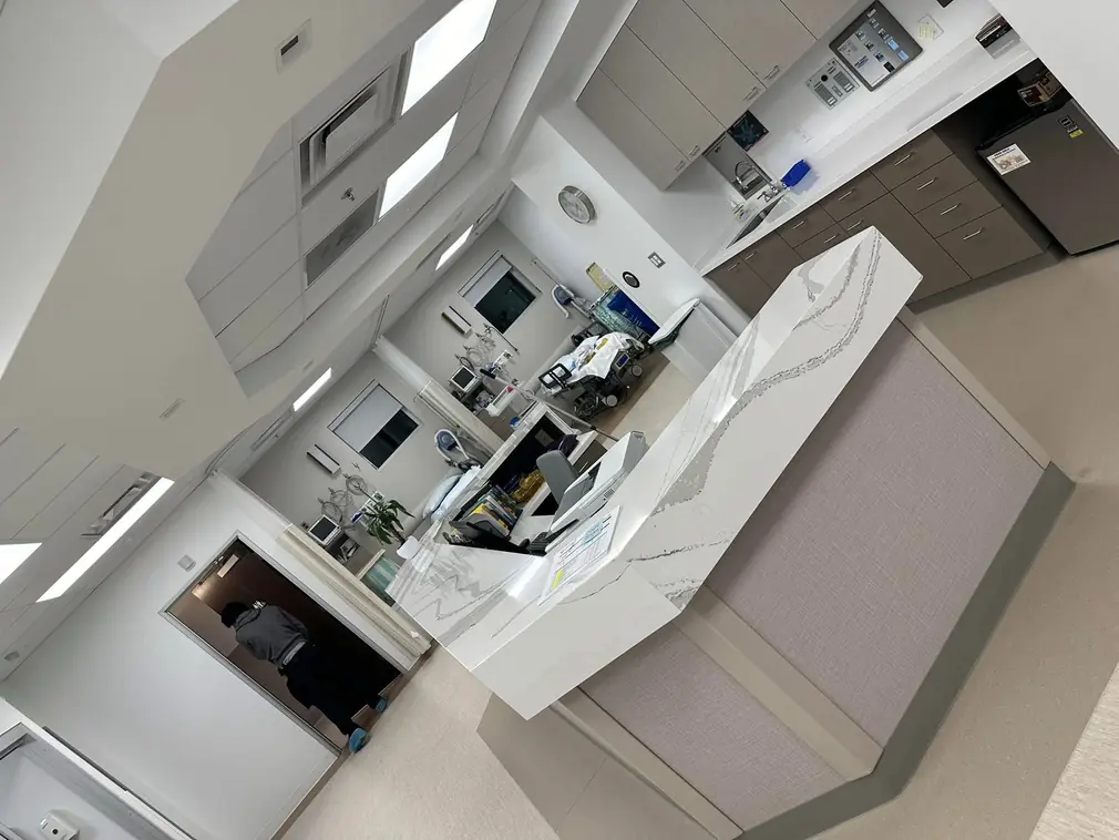 Bright, clean medical reception desk and nearby treatment bays showing sanitized counters, cabinets, and equipment