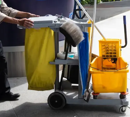 Janitorial cart with mop bucket, cleaning supplies, broom, and trash bag ready for commercial cleaning services