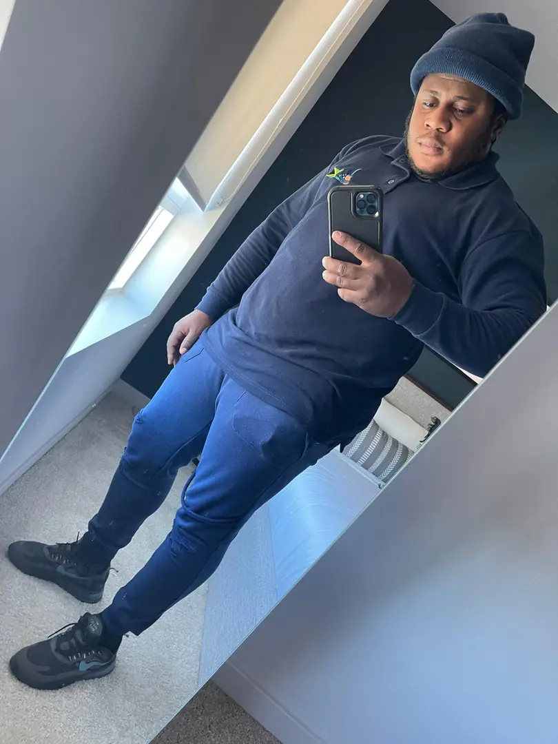 Yardie Cleaning employee in navy uniform taking a mirror selfie in a bright room, mobile phone visible